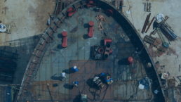 Vista aerea di un cantiere industriale con operai al lavoro su una struttura metallica, illustrando la gestione asset cantieri.